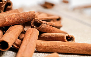 Closeup detail - Heap of cinnamon bark sticks on linen tablecloth.