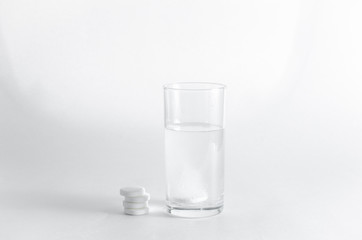 The effervescent tablet dissolves in a glass of water. A stack of drugs isolated on a white background. Treatment of viral diseases. Help with depression and insomnia. Liquid multivitamins