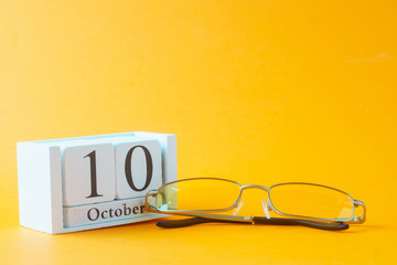 Glasses and wooden calendar, world view day, concept, on orange background