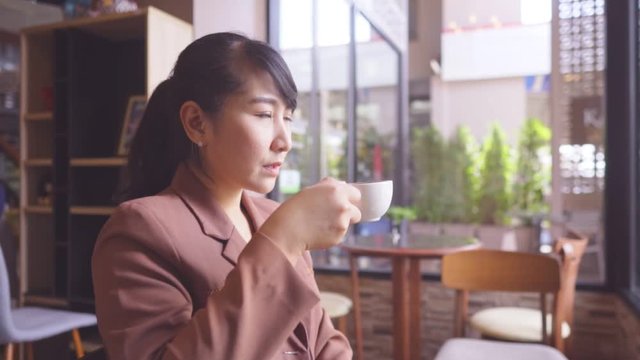 Young asian women  near big window in coffee shop during free time and working on tablet 