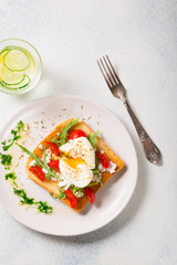 Healthy breakfast. Poached egg on toasted toast with a glass of detox lemon cucumber water. copy space