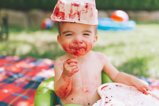 A Happy And Messy Baby Eating Blackberries In The Summer. 