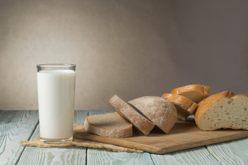 Glass of milk and slices of fresh bread on a wooden board