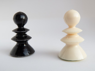 One white and one black chess piece standing opposite each other