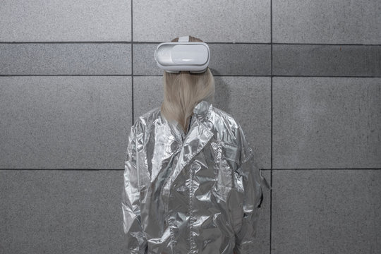 Rear view of girl in silver suit wearing VR goggles on back of head