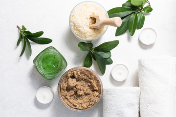 Spa and wellness concept. Natural scrubs for face and body, aromatic sea salt, towels and candles on white background top view. Organic handmade cosmetic products.