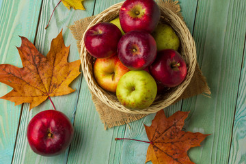 Basket with green and red apples on a wooden table, top view