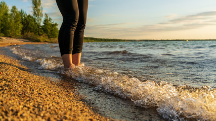 Feet of a woman barefoot on a beach at the water