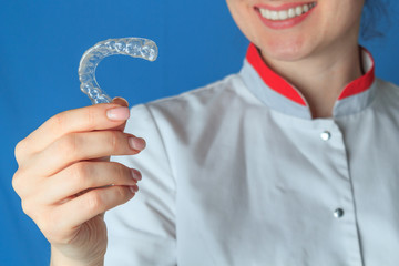 Kappa for teeth whitening in the hands of a dentist, on a blue background
