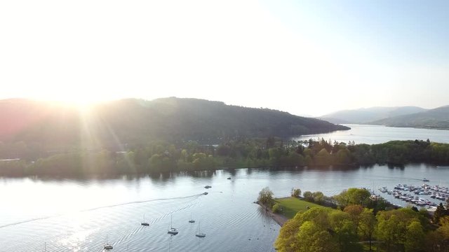 4K Sunset over fishing boats on Scottish lake in the Highlands. Moored and sailing boats on water with blue sky in a British summer tourist nature landscape
