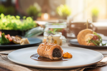 Different tasty dishes on the restaurant table, meat roll on the plate
