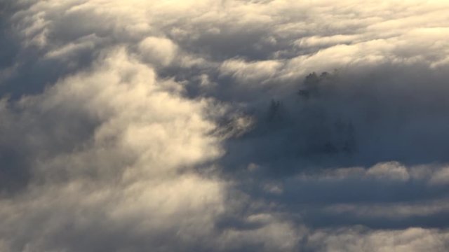 Rolling cloud inversion time lapse with mountain peaks poking through the surface