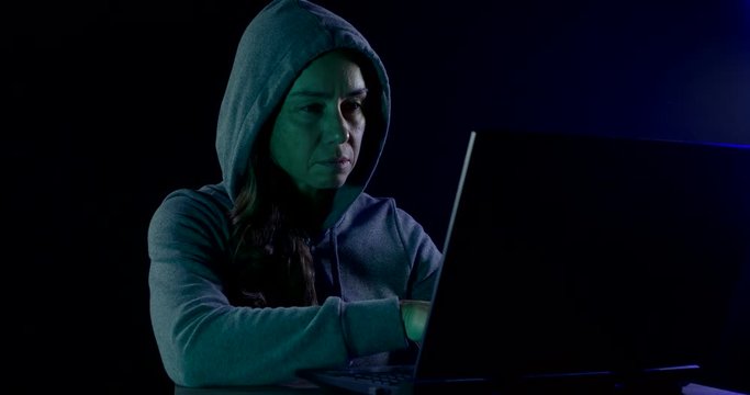 female hacker is working with notebook in dark room in night