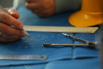 Male hand holding pencil in hand. Engineering blueprint design for buildings of blue architecture...