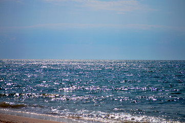 Sun reflecting on sea tide and waves on the seashore at the sunny day 
