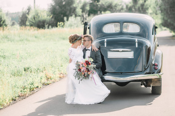 The bride and groom are sitting on a car.