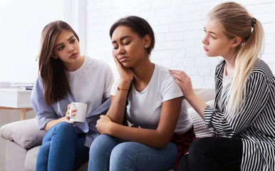 Teen girls comforting their upset friend at home