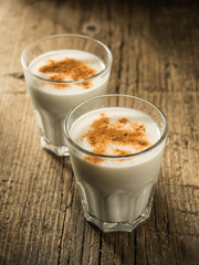 Eggnog. Traditional Christmas drink made from raw chicken eggs and milk with cinnamon in glass.