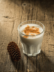 Eggnog. Traditional Christmas drink made from raw chicken eggs and milk with cinnamon in glass.