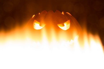 Spooky carved halloween pumpkin in hot burning hell fire flames. Big helloween autumn symbol with...