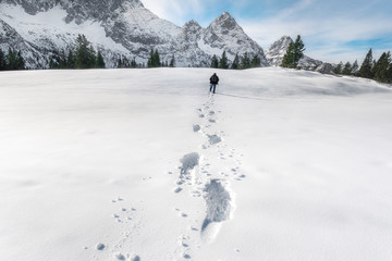 Snow footprints in the Alps mountains. Winter wandering scenery