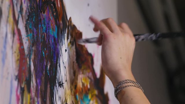 Artist designer draws an eagle on the wall. Craftsman decorator paints a picture with acrylic oil color. Close-up dark magic cinematic look.