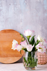 Eustoma flowers in vase on table near stone wall, space for text. Blank for postcards