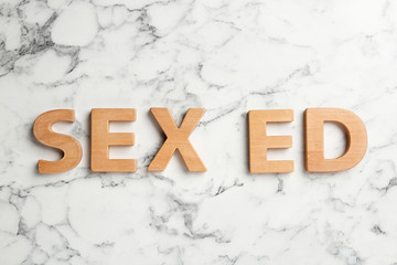 Phrase "SEX ED" made of wooden letters on marble background, flat lay