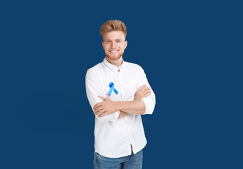 Young man with ribbon on blue background. Urology cancer awareness