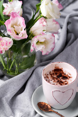 Having a cup of coffee with chocolate, flowers eustoma on blanket in bed. Holiday concept