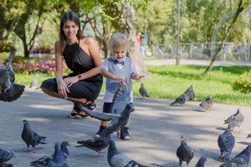Little boy surrounded by pigeons in the park.