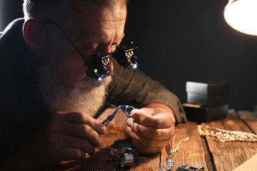 Male jeweler evaluating diamond ring in workshop