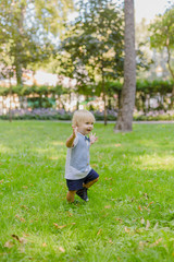 Naklejka na ściany i meble Happy little boy on a green lawn in a park.