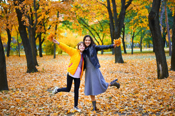 woman having fun with autumn leaves in city park, outdoor portrait