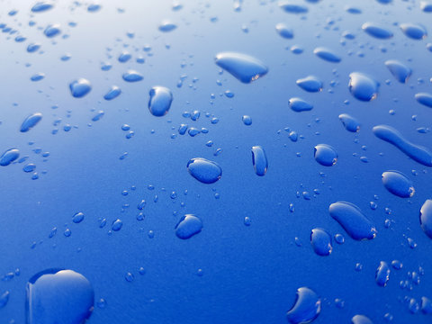 Drops of rainwater on blue metal background after nanoceramics polishing technology closeup