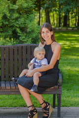 Fototapeta premium Beautiful young mother with a little son on a bench.