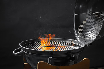 Modern barbecue grill with burning fire on dark background - obrazy, fototapety, plakaty