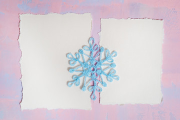 Christmas background with blank notebook, Blue crocheted snowflake, handmade on a purple-pink background. Mockup torn paper trend. Flat lay, top view. copy space.