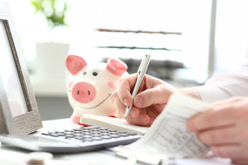 Male hands making notes with silver pen about family budget closeup