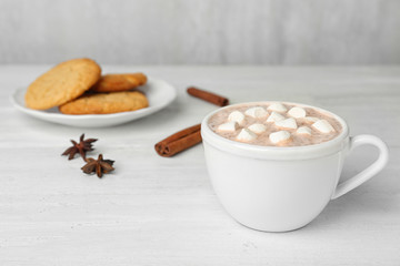 Delicious hot cocoa drink with marshmallows in cup on white wooden table