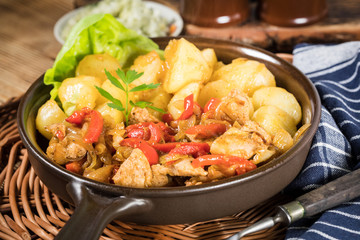 Fried pieces of chicken with red peppers and onions.