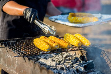 cook in gloves fry corn on an open barbecue fire