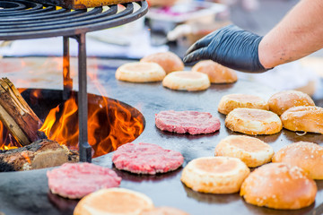 cook hands in gloves grill burger beef patties on the grill. Open fire on the barbecue