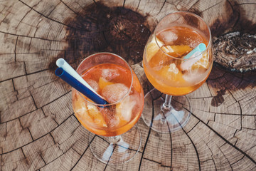 Aperol spritz in wine glasses, with straw, on wooden table. Alcohol free.