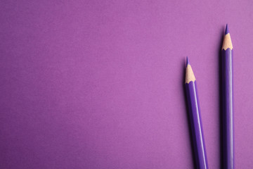Flat lay composition with color pencils on purple background. Space for text