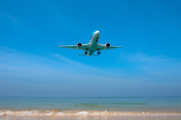 Fototapeta na wymiar An airplane lands on a flight flying over Mai Khao Beach in Thailand.