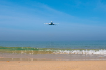 Fototapeta na wymiar The plane flies over the Mai Khao Beach in thailand. Below is soft sand and a blue sea with nice waves.