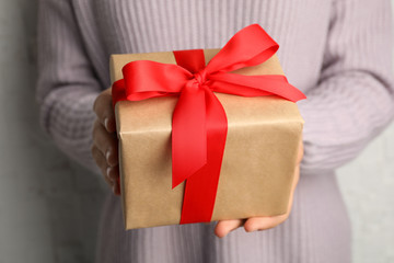 Young woman holding Christmas gift, closeup view