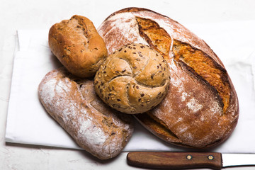 Tasty dark bread and buns  on white background, copy space. Bakery products, wholemeal bread and brown whole wheat buns