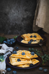 Square Belgian waffles with blueberries on a dark background